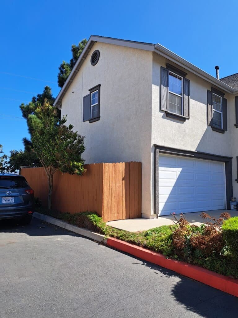 Bright white house with dark gray window shutters, freshly painted exterior, and a clean garage door.