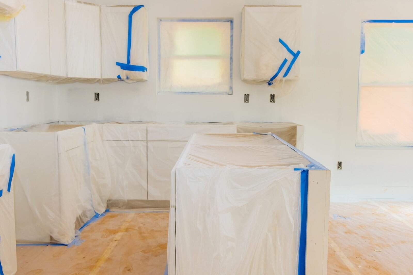Bright white interior wall painting with cabinetry wrapping process in progress for a modern kitchen renovation.