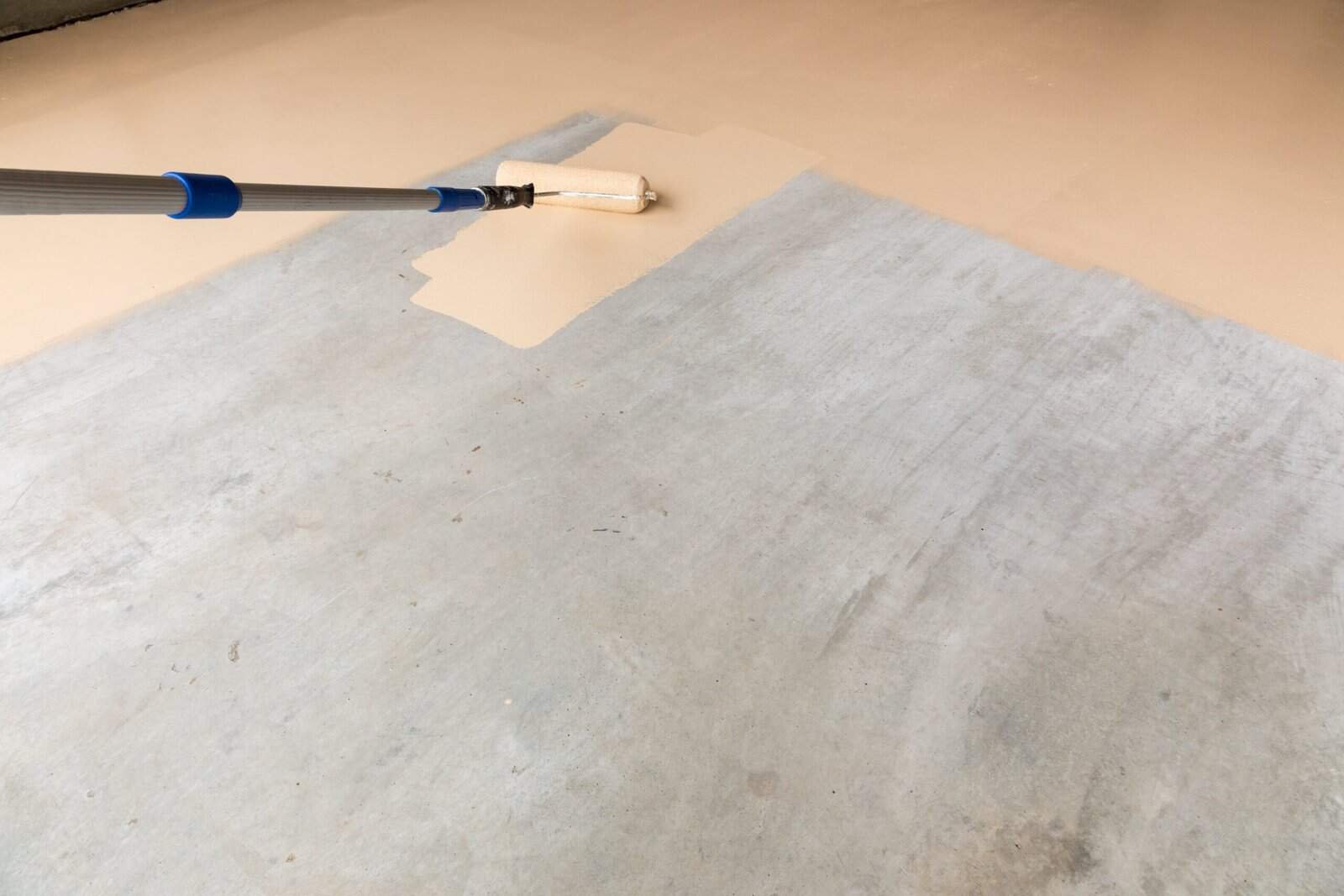 Paint roller applying beige paint over a gray surface for professional home painting services.